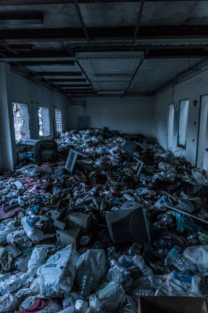 Decrepit indoor room cluttered with heaps of garbage and waste materials.